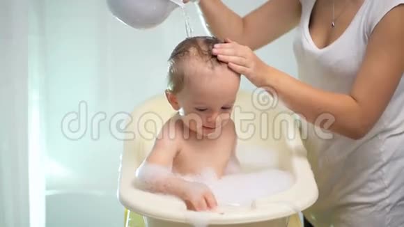母亲在浴缸里给婴儿倒水的慢镜头视频的预览图