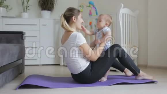 一位年轻的女士在健身垫上锻炼抱着她可爱的小儿子视频的预览图