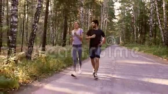 美丽的女人和英俊的男人早上在绿色森林里慢跑视频的预览图