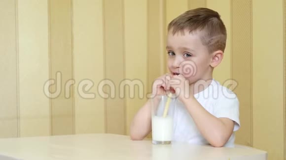 一个快乐的孩子通过吸管从杯子里喝牛奶视频的预览图