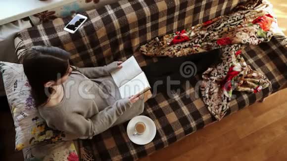 沙发上那个拿着咖啡和书的女孩视频的预览图