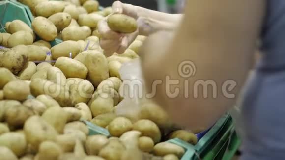 女性双手将成熟的土豆放入透明塑料包装袋中女人选择成熟的土豆加在包装上视频的预览图