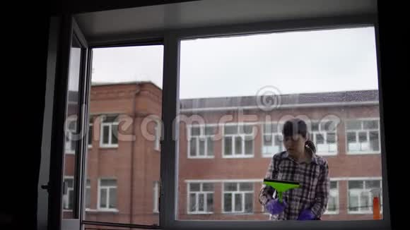幸福的肖像年轻的女人在家里打扫窗户视频的预览图