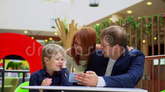 技术和人这家人在购物中心的食品场吃饭父亲和儿子坐在小桌旁视频的预览图