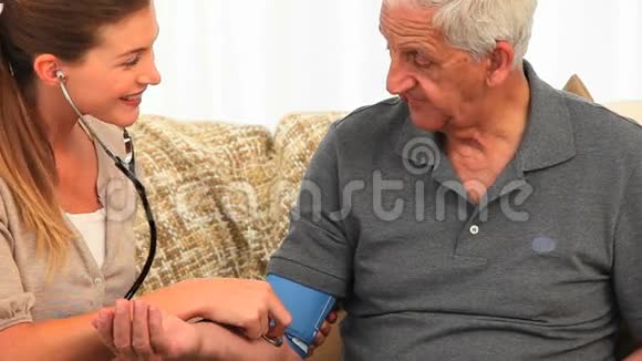 微笑护士测量她的男性病人的血压视频的预览图