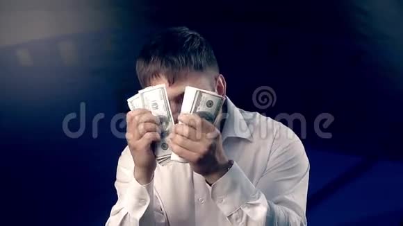 一个男人把脸藏在数钱的扇子后面的肖像视频的预览图