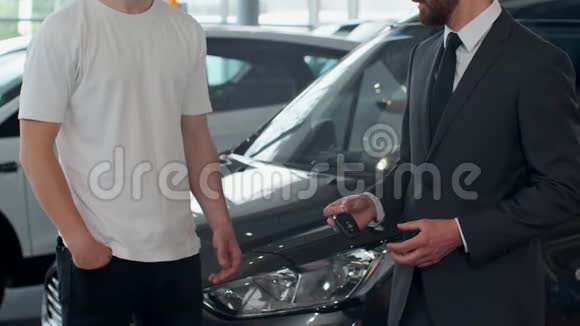 男子手把车钥匙交给男子手在汽车经销店关门不承认的汽车销售商和一个买了视频的预览图