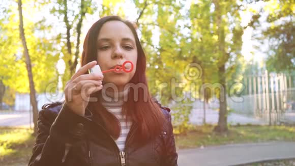 女人在户外吹肥皂泡在公园里玩得开心的少女吹肥皂泡视频的预览图