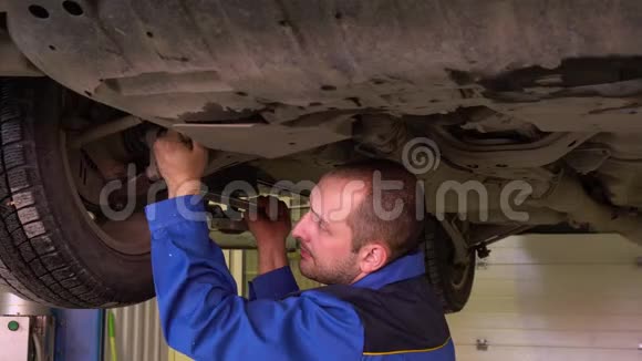 汽车机械师穿着蓝色长袍修理汽车悬架在车库特写视频的预览图