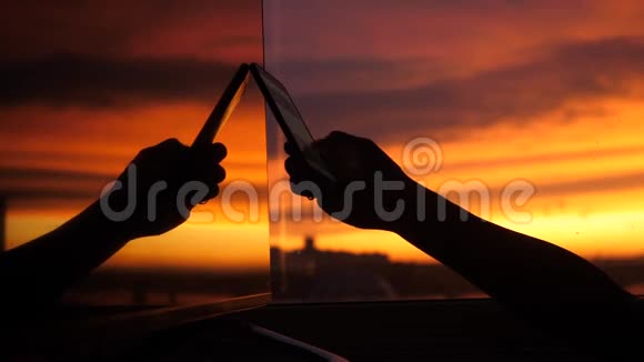 女性的手使用智能手机在夕阳的背景下反射窗口3840x2160视频的预览图