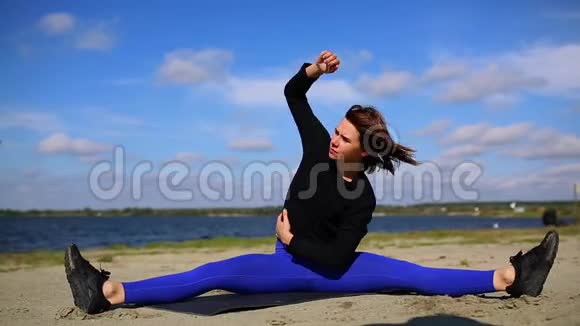 河岸上的女孩在经过一次艰苦的锻炼后进行肌肉的伸展和放松健身和瑜伽视频的预览图