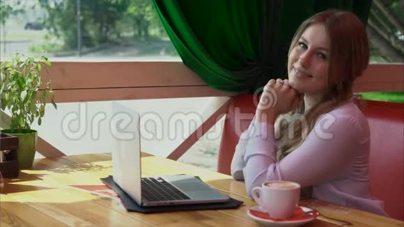 咖啡馆里年轻商务女性带着笔记本电脑微笑的视频画像视频的预览图