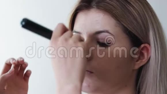 女人用大刷子涂化妆品的特写女孩在沙龙化妆涂粉在皮肤上视频的预览图