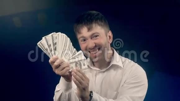 年轻的快乐男人挥舞着一把美元视频的预览图