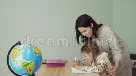 年轻的母亲帮助她的小女儿做家庭作业视频的预览图