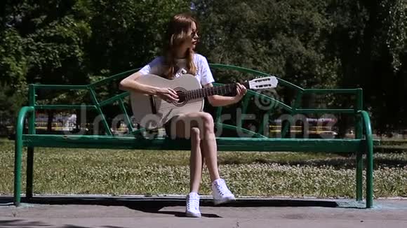 美丽的年轻时髦女孩在公园玩吉他视频的预览图