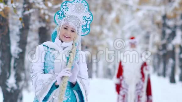 美丽的雪少女在前景玩她的头发和弗罗斯特神父在背景视频的预览图