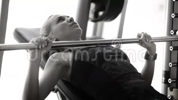 一个女人在健身房举起杠铃的黑白镜头视频的预览图