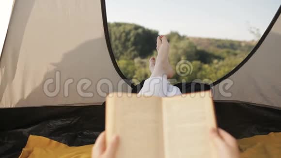 年轻女子在帐篷里休息看书了解大自然视频的预览图