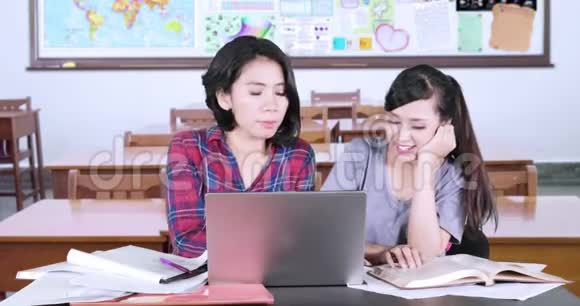 两个女学生在教室里一起学习视频的预览图