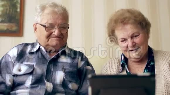 成熟的老夫妇享受现代技术使用平板电脑老年人在家里与互联网交流视频的预览图