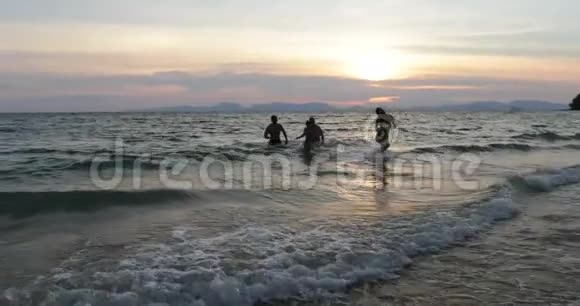 在夕阳下的沙滩上人们从海上奔跑快乐地混合着种族朋友视频的预览图
