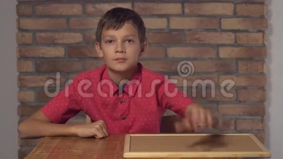 坐在书桌前的孩子拿着一张挂图上面写着红色的砖墙视频的预览图