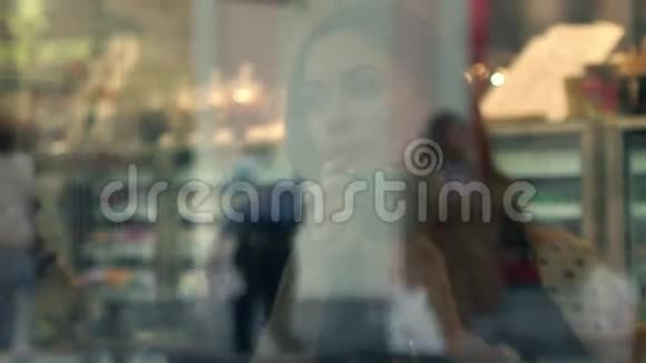 美丽的黑发女孩在小咖啡馆喝热巧克力从外面透过窗户观看4K视频视频的预览图