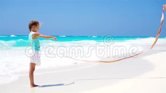 可爱的小女孩在海滩上玩体操丝带流动人口视频的预览图