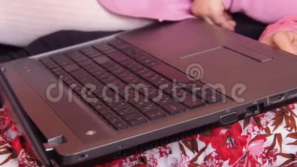 母亲带着两个女儿躺在一张带笔记本电脑的橙色沙发上视频的预览图