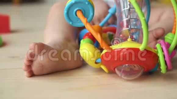 五颜六色的玩具躺在坐在地板上的小男孩的脚之间视频的预览图