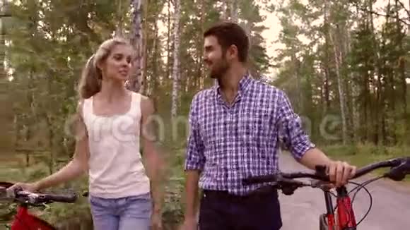 微笑的女人和英俊的男人抱着自行车走在一起视频的预览图