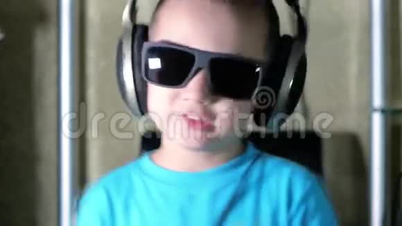 戴墨镜的男孩戴耳机听音乐视频的预览图