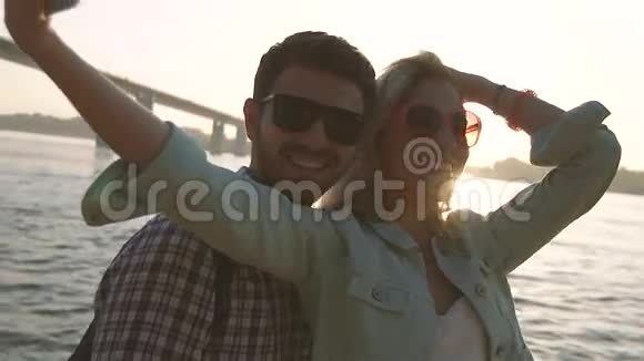 可爱的旅行情侣在河桥上自拍视频的预览图