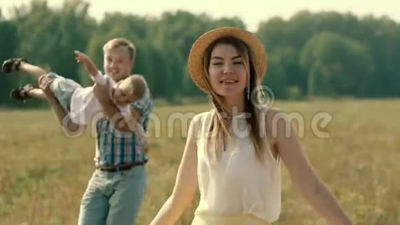 美丽的金发年轻的母亲旋转着她的丈夫和儿子在后台视频的预览图