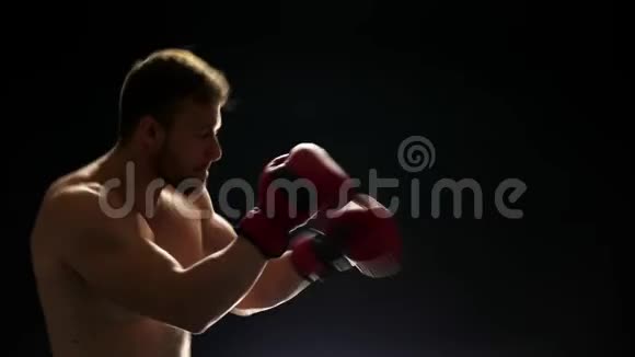 年轻的拳击手正在黑暗的背景下训练视频的预览图