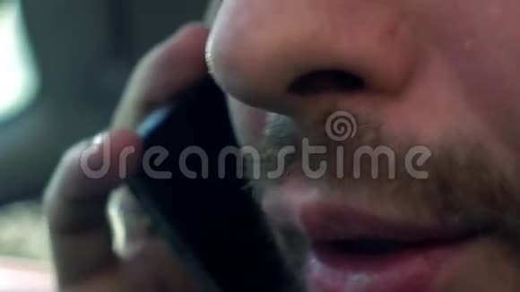 一个留着胡子的年轻人在车里用手机说话毫不费力4K特写视频视频的预览图