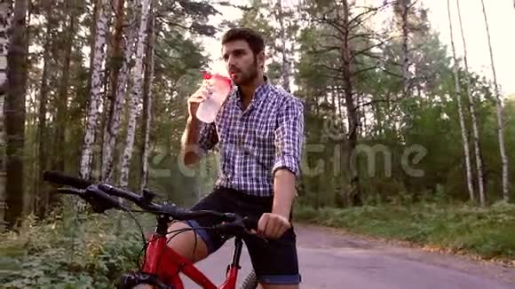 坐在自行车和饮用水上的英俊男子的肖像视频的预览图