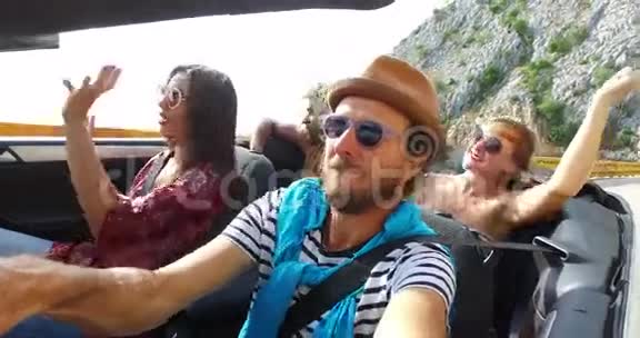 戴着帽子的大胡子男和朋友在山区高速公路上开车视频的预览图