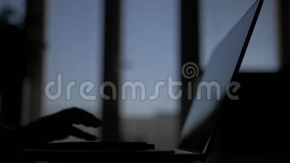 一个女人的特写在深夜她的手在笔记本上写字笔上有笔记本电脑显示器背景上视频的预览图