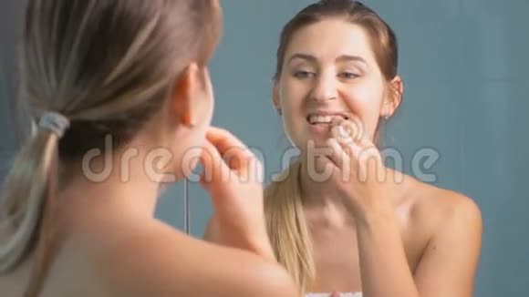 4K镜头显示年轻女子在浴室的镜子前检查牙齿视频的预览图