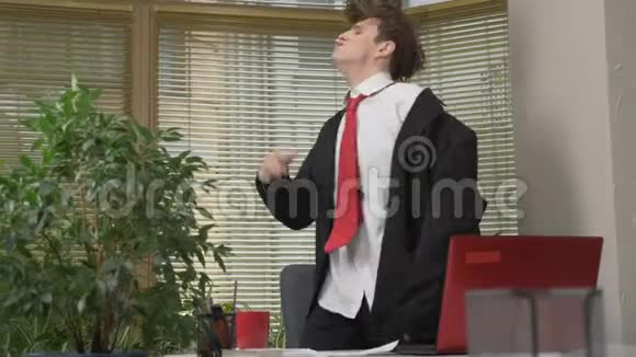 穿西装的年轻人在办公室里跳舞做滑稽的脸傻瓜快乐办公室工作概念60fps视频的预览图
