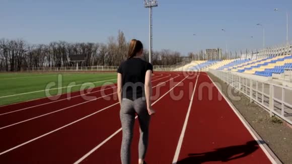 年轻有魅力的运动女性在体育场慢动作慢跑在阳光明媚的春天户外锻炼视频的预览图