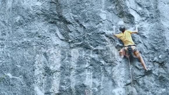 攀岩者开始爬在悬崖上寻找到达和抓住视频的预览图
