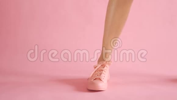 在珊瑚色背景下穿着运动鞋的身材匀称的女性腿视频的预览图
