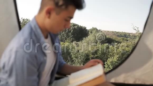 森林露营地帐篷里的青年游客读本视频的预览图