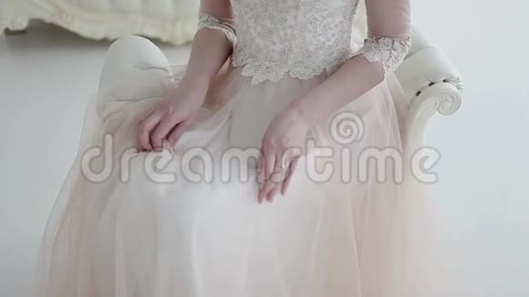美丽的新娘坐在椅子上一条茂盛的花边裙子特写抚摸裙子的手婚纱礼服视频的预览图
