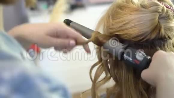 一个发型师给一个女人做一个发型让她卷发特写视频的预览图