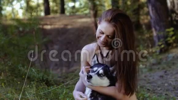 漂亮的皮肤白皙的年轻女人盘膝而坐抱着狗很开心视频的预览图