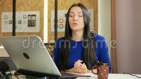 在电脑办公室工作的漂亮女人她看着相机和顾客说话长长的深色头发视频的预览图